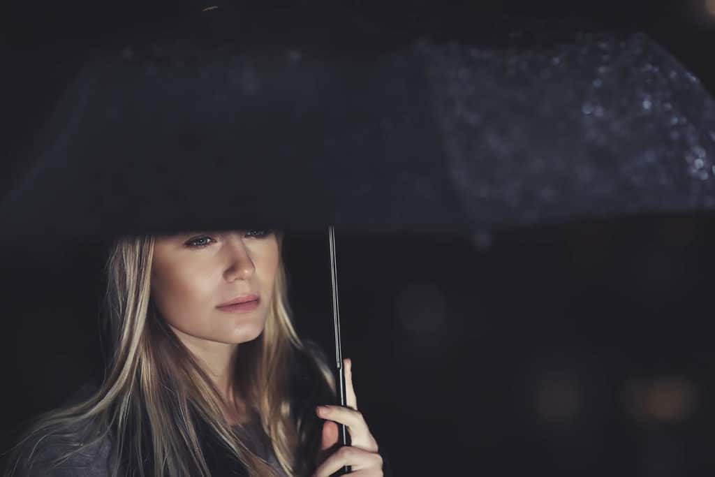 Sad woman holding an umbrella looking into a distance