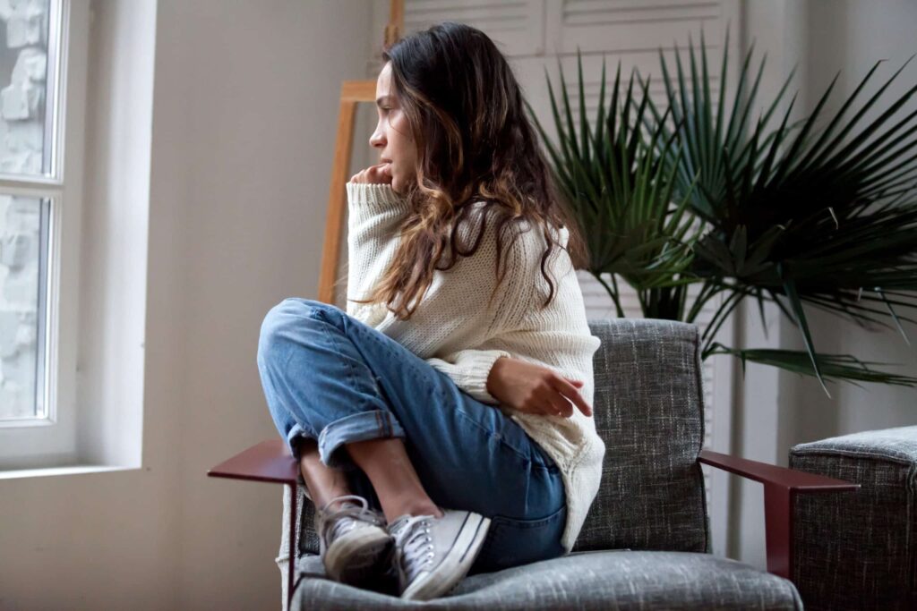 A woman looking distraught looks out the window, seeking help at a mental health day treatment program in Worcester.