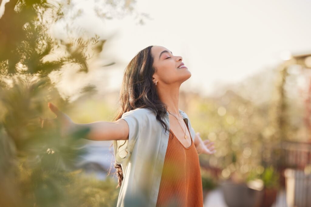 Young woman with benzodiazepine addiction getting outdoors with her arms outstretched breathing in fresh air.